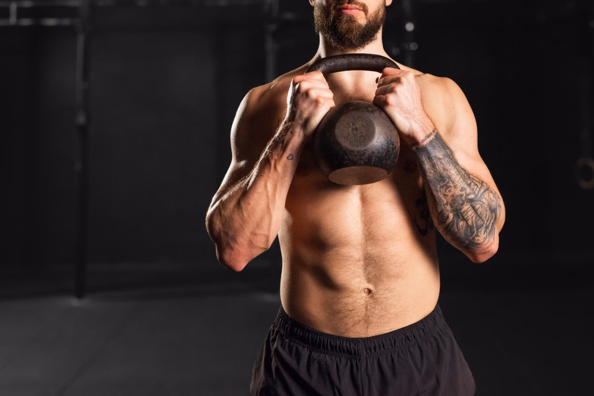Man holding a kettlebell at his side in a gym