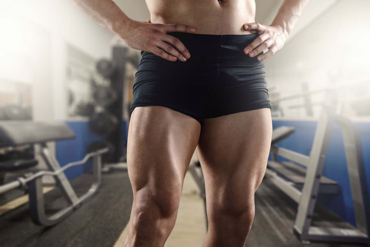 Close-up of a man's muscular legs standing in a gym