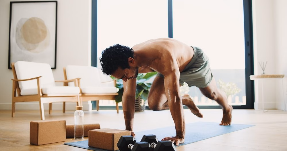 Man doing mountain climbers on a yoga mat at home, an example of a bodyweight HIIT move