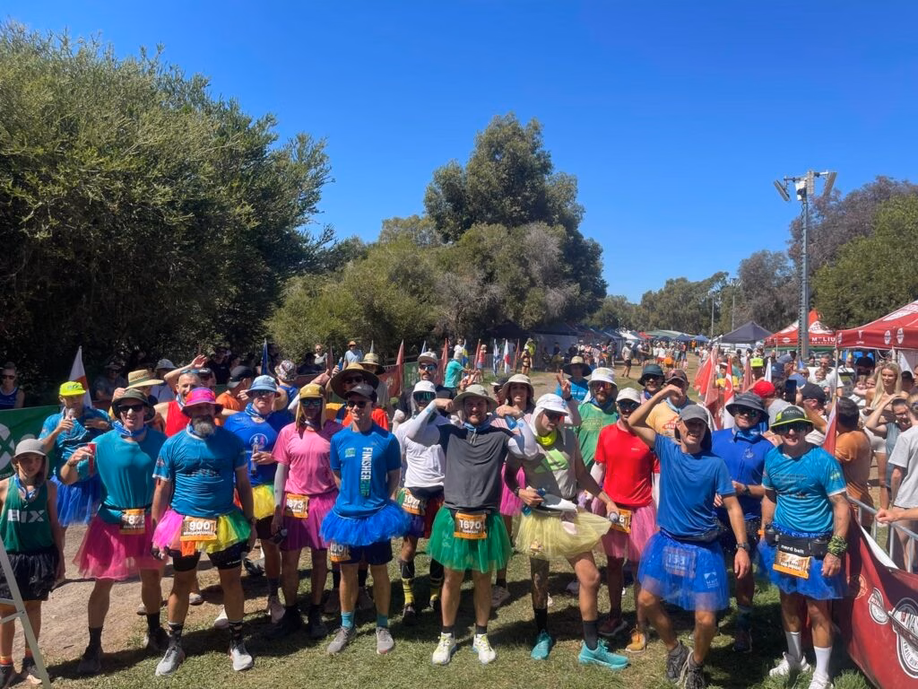 A group of backyard ultra runners posing in colourful tutus