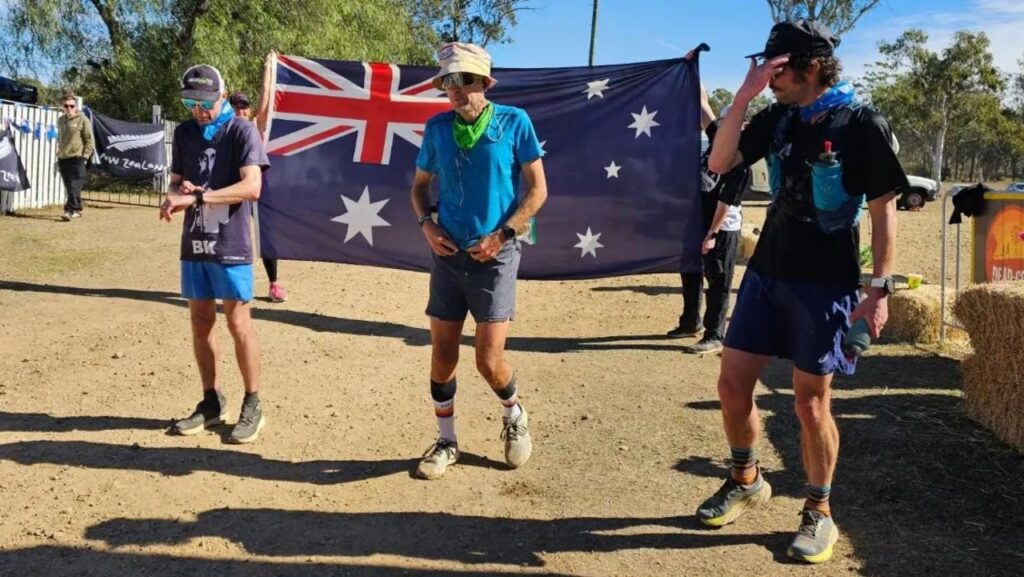 Runners walking past an Australian flag between yards at a backyard ultra
