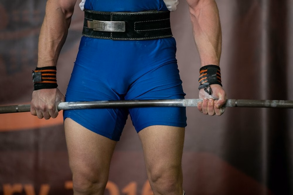 Powerlifter gripping a barbell with wrist wraps before a deadlift