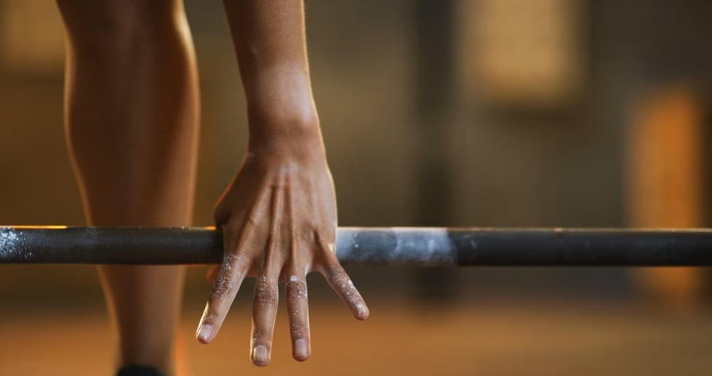 Chalked hand gripping a barbell during a lift