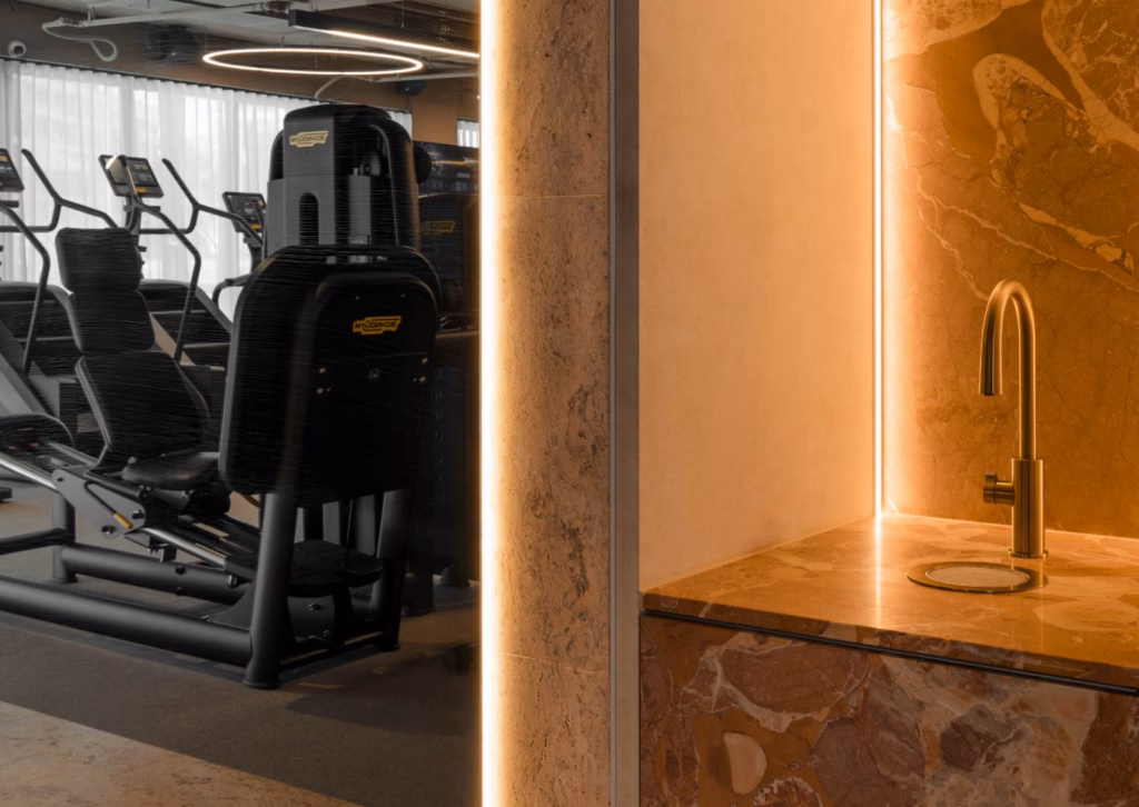 Standard gym equipment beside a marble, gold-tapped luxury finish, illustrating the contrast at the centre of Level X's pitch