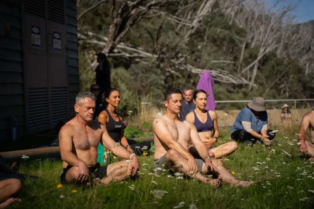 A group sitting in a grassy field during a post-hike recovery and breathwork session