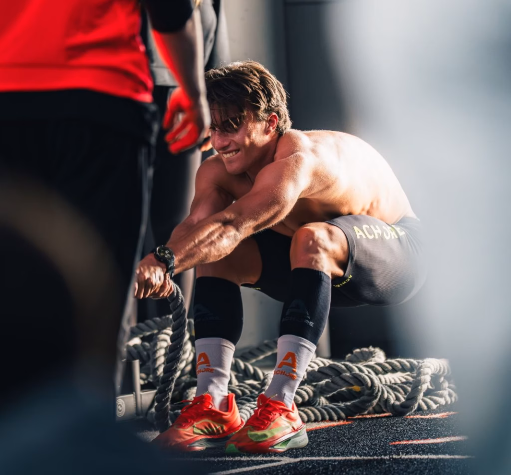 An athlete gripping a rope during sled pull training, gritting their teeth