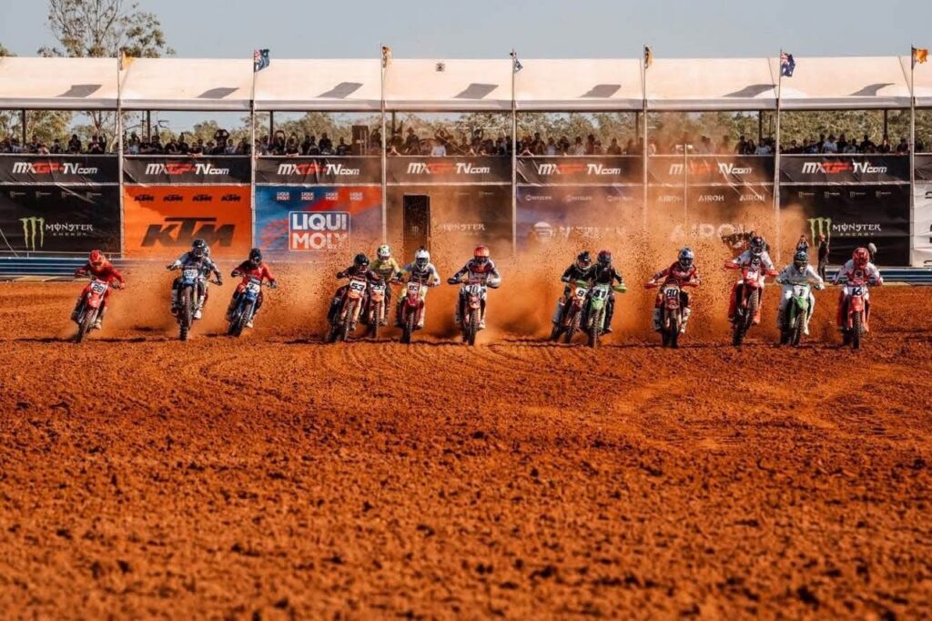 Pack of MXGP riders launch off the start gate at Hidden Valley Motorsport Complex in Darwin, with a packed grandstand behind them