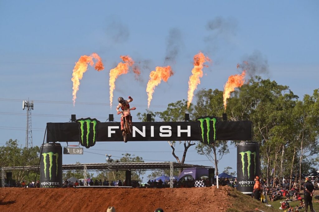 A motocross rider jumps through Hidden Valley's flame-lit finish gate, branded with Monster Energy signage