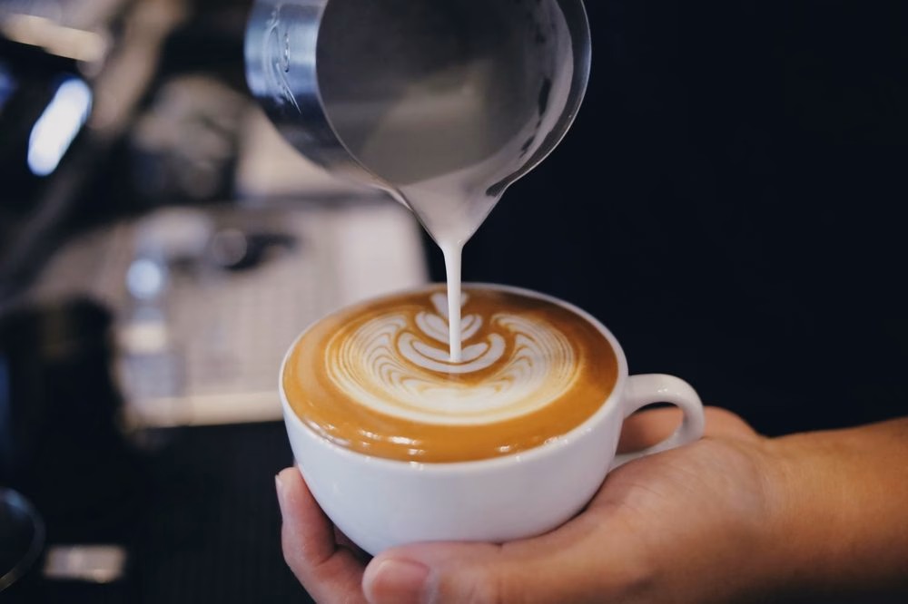 Barista pouring latte art into a cup of coffee