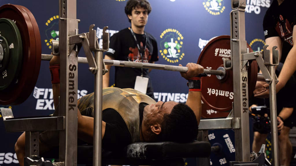 A competitor performing a bench press lift at a powerlifting competition