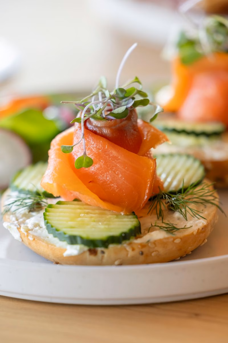Smoked salmon, cucumber slices, dill and micro herbs on a bagel half with soft cheese