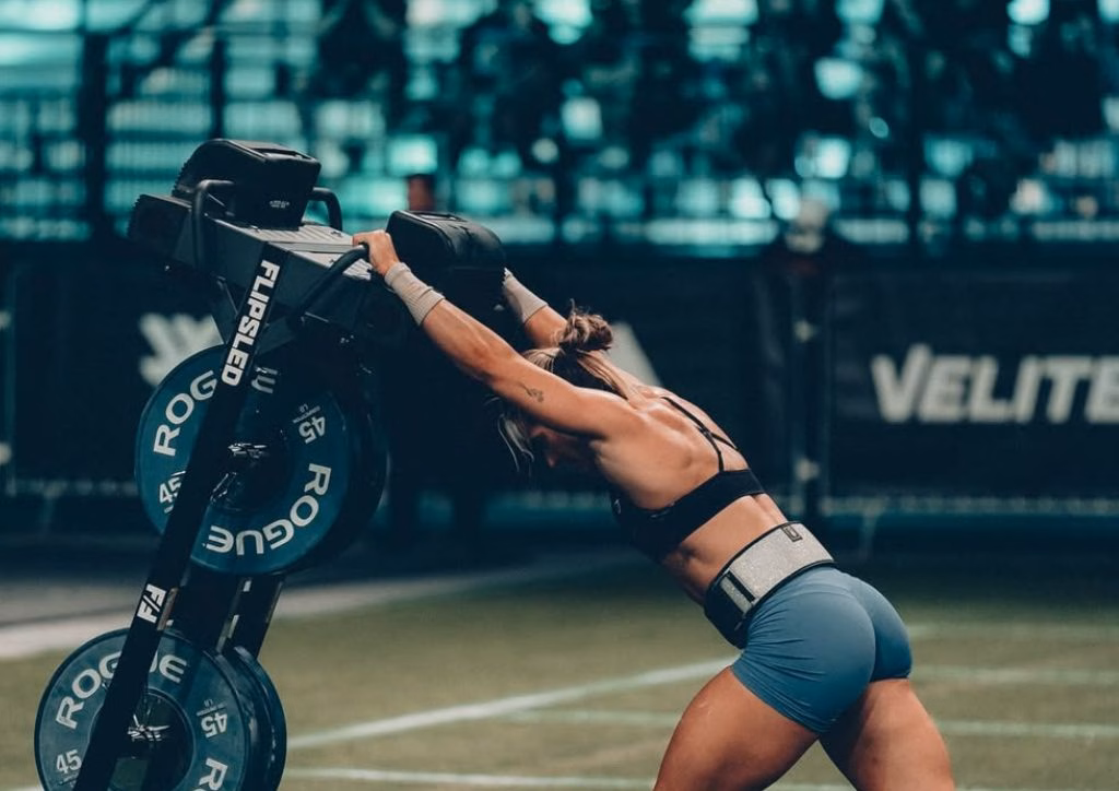 Aimee Cringle pushing a sled loaded with Rogue weight plates