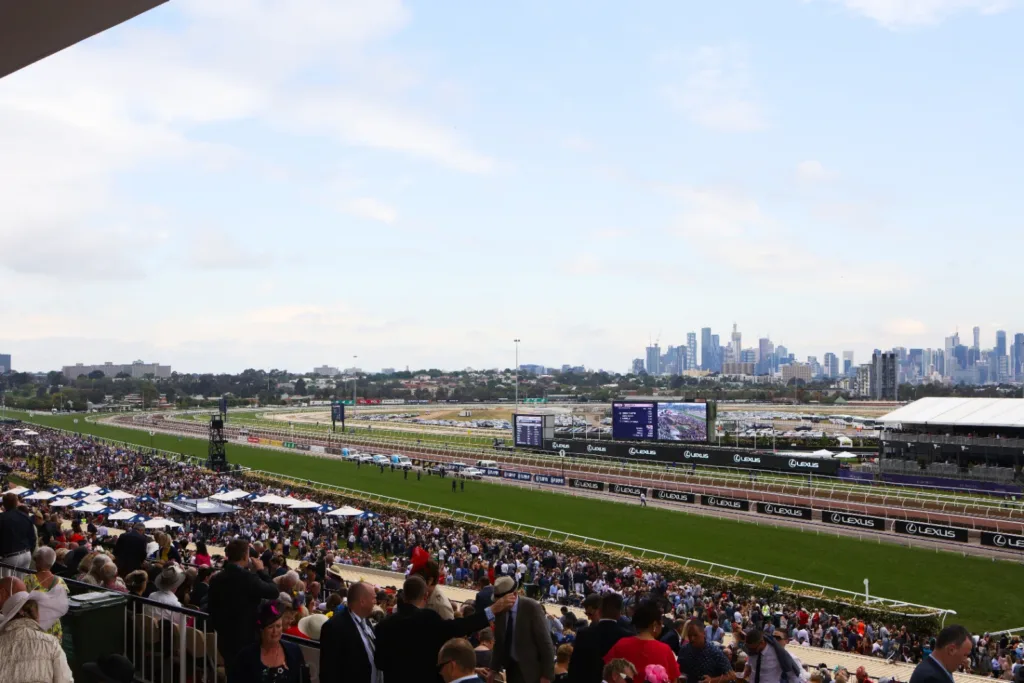 Crowds in the grandstand at Flemington Racecourse, with the Melbourne skyline behind the track