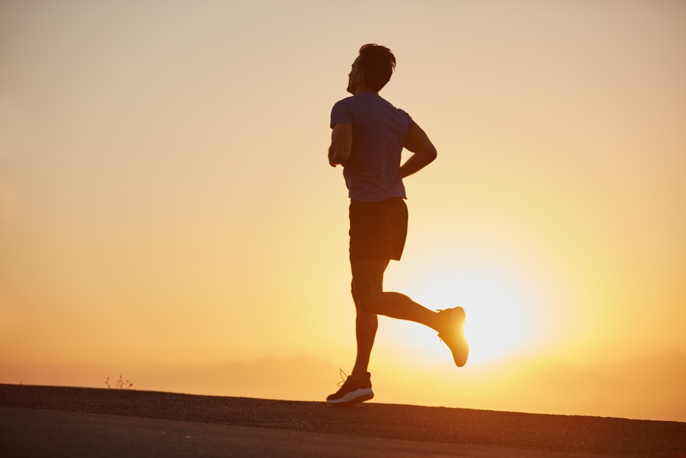 Silhouette of a man running along a road at sunset